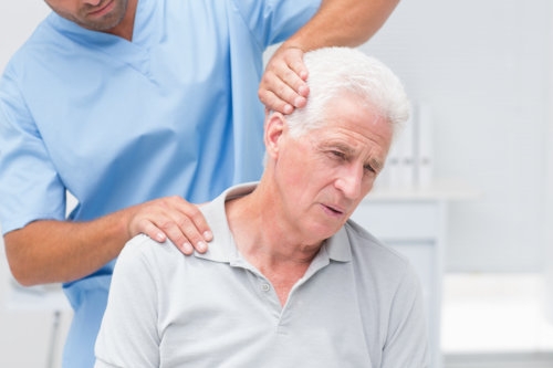 Physiotherapist giving physical therapy to senior male patient in clinic